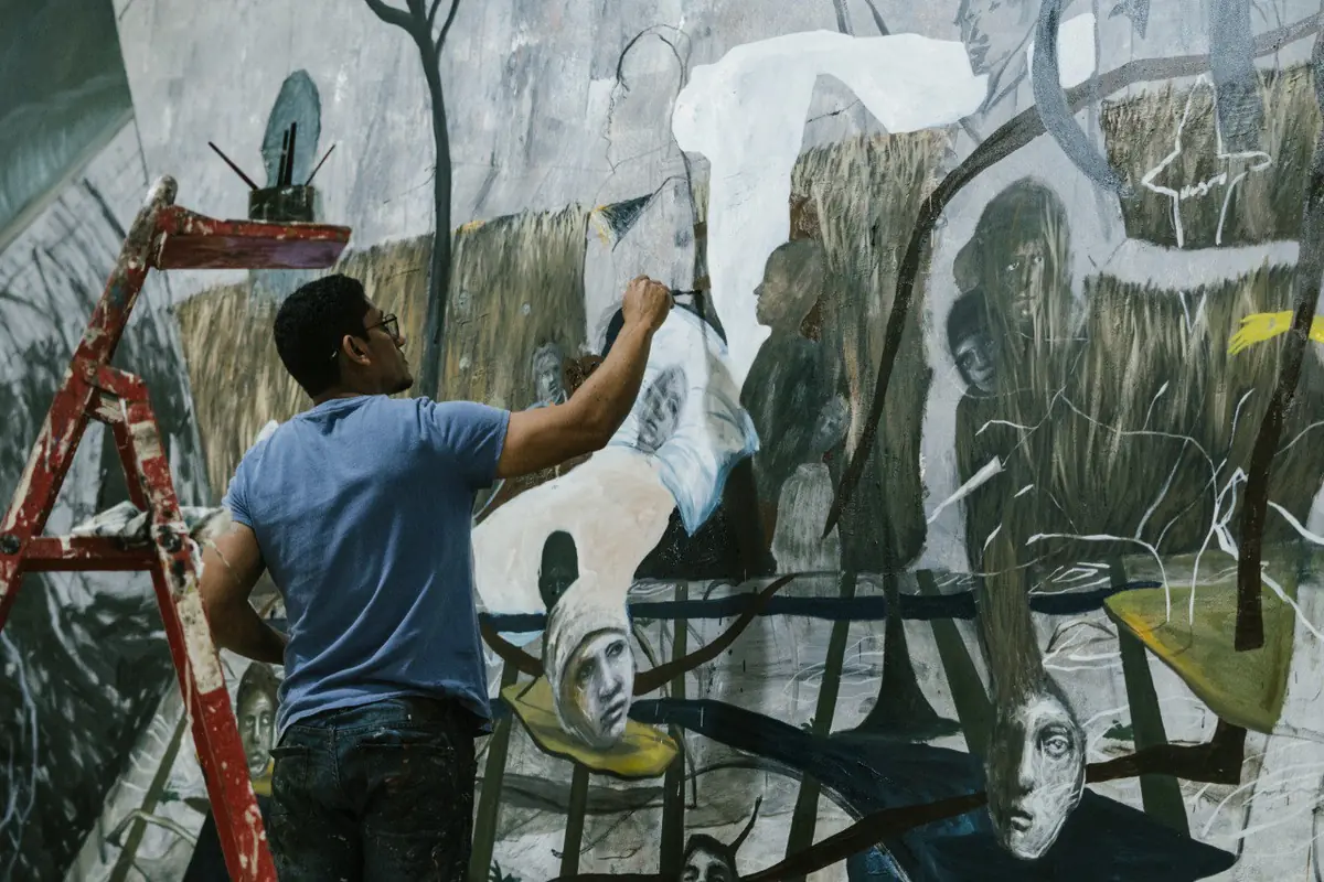 The artist working on a mural populated by suspended creatures